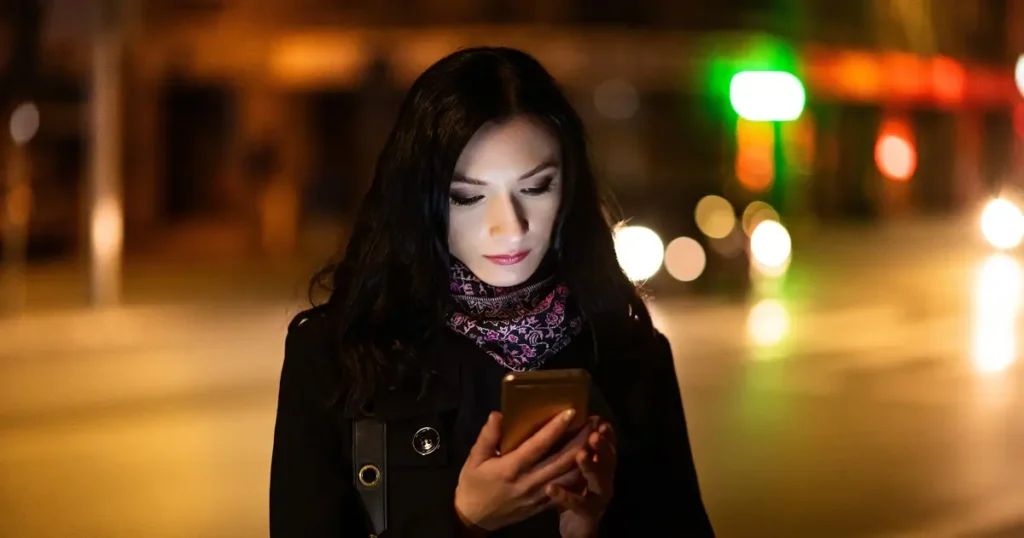 Woman using smartphone at night while waiting for a rideshare