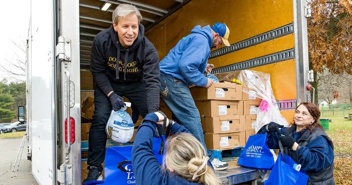Volunteers distribute frozen turkeys and food boxes from the back of a truck to community members during a holiday food giveaway.
